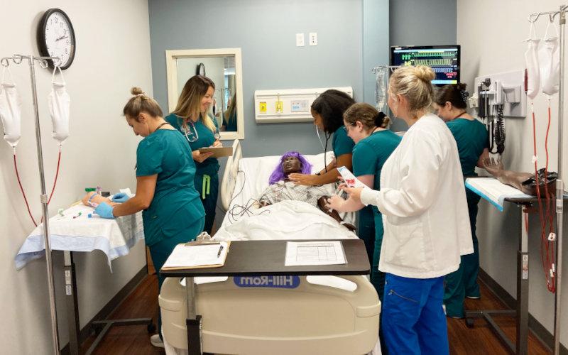 A nursing lab with students around a simulation patient.